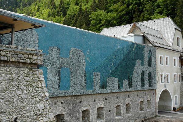 Dekorativer Schutz eines historischen Gebäudes schützende Membranfassade mit Abbildung der eigentlichen Ruine hinter der Membran in Reutte, Österreich.